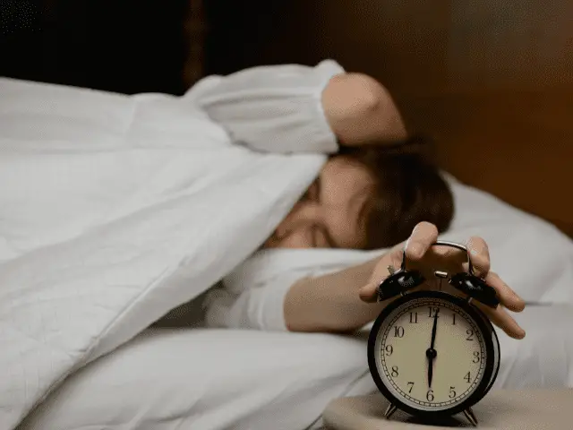 Man turning off alarm clock