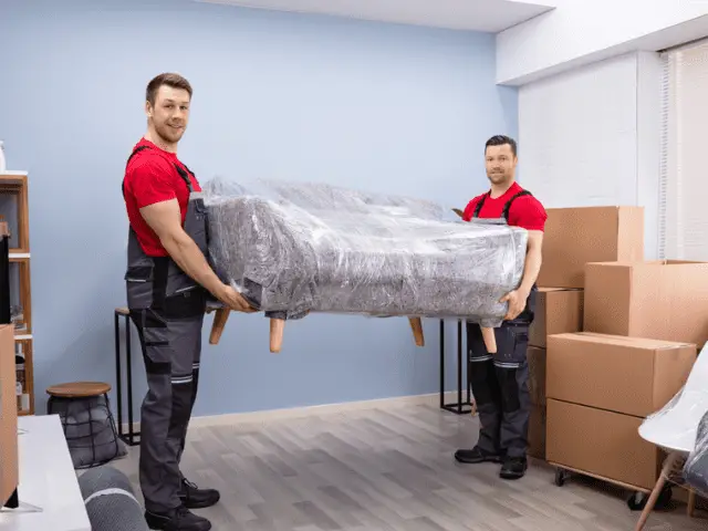 Movers Carrying a Couch Wrapped In Plastic